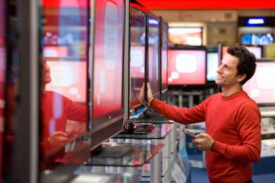 Man holding remote looking at TV within a retail store