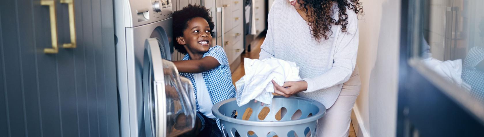 Child and adult unloading clothes dryer in kitchen