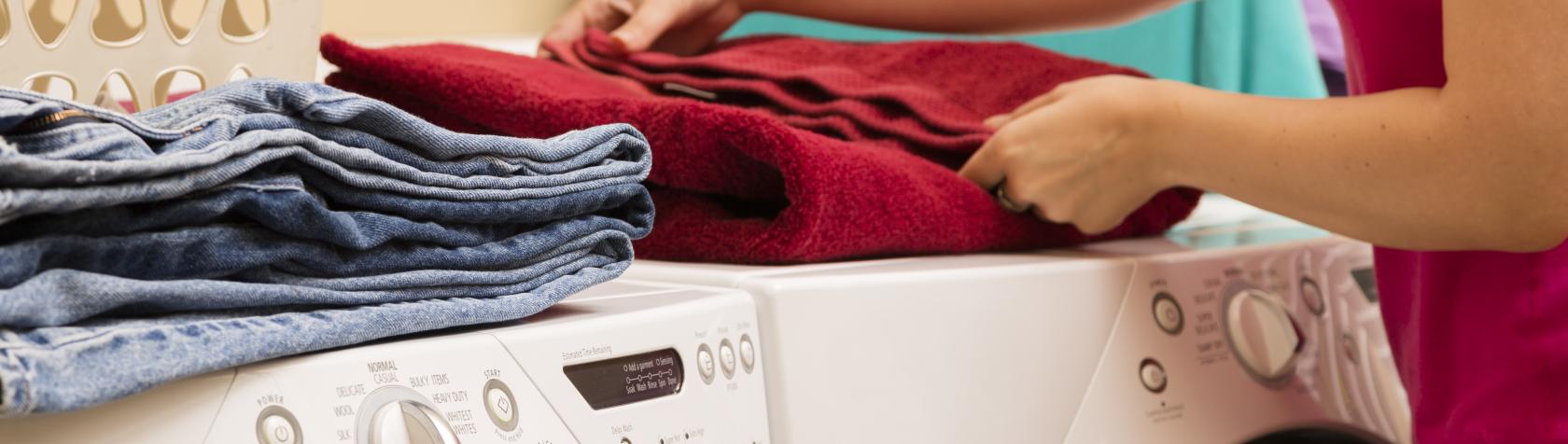 Adult folding towels from clothes dryer with laundry basket