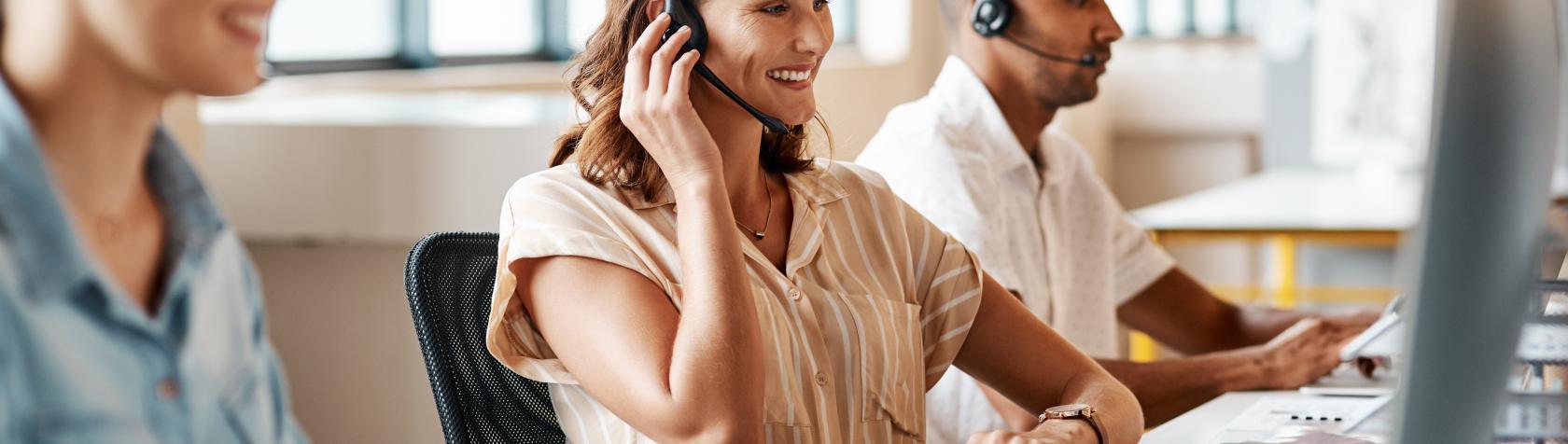 Shot of a young adult using a headset and computer in a modern office